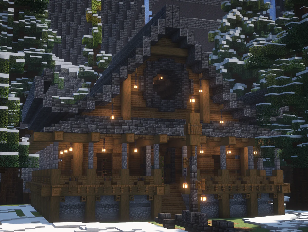 Casa de madera y piedra iluminada entre árboles nevados en Minecraft
